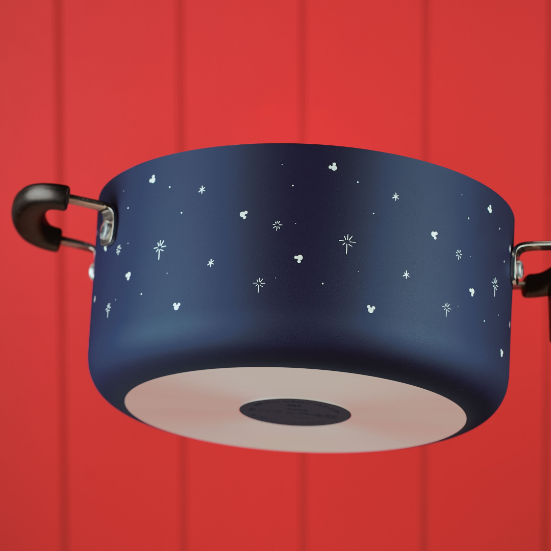 Blue pot with star pattern, black handles, and red wooden background.