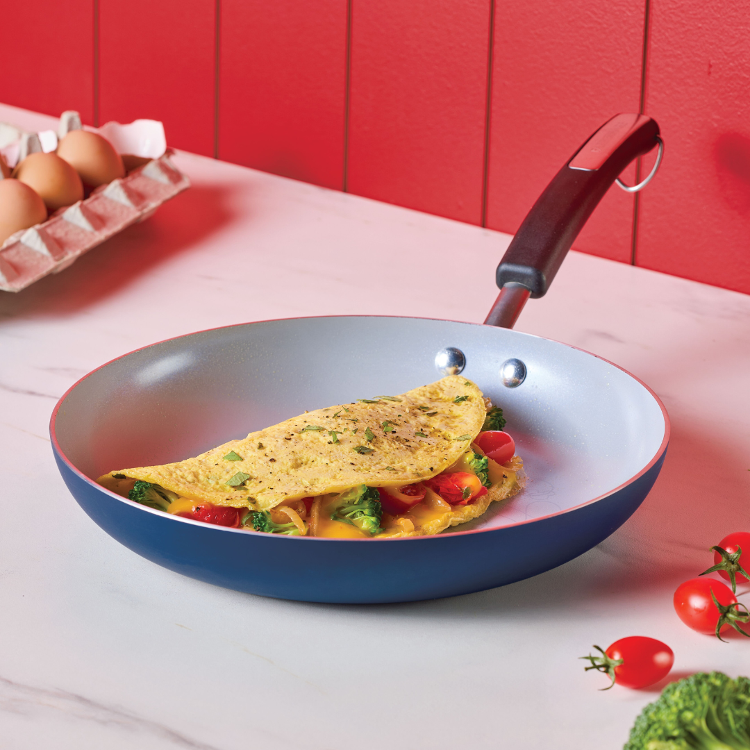 Omelette with veggies in a non-stick pan on a kitchen counter.