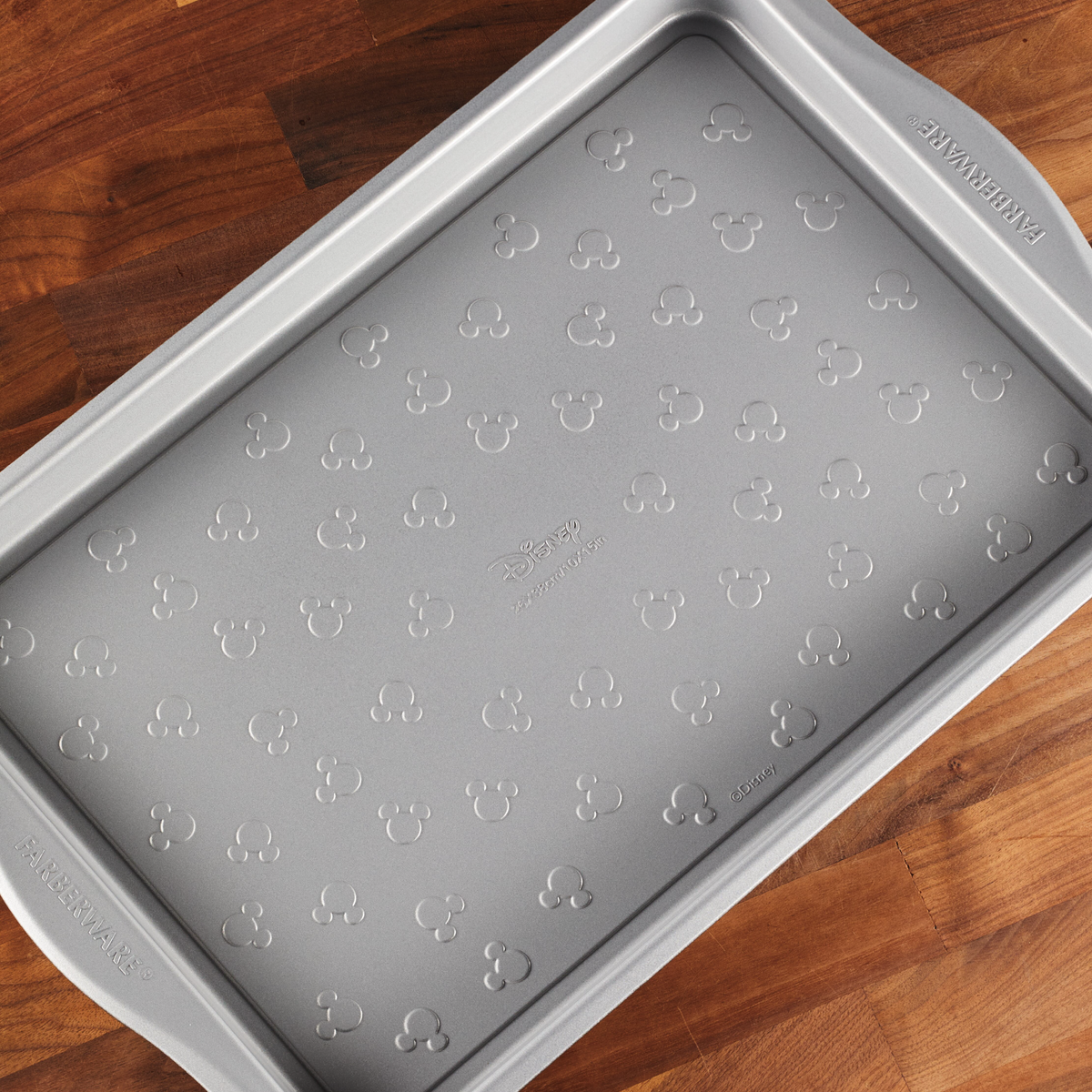 Gray baking tray with embossed Mickey Mouse pattern on wooden surface.