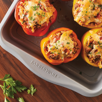 The appetizing stuffed bell peppers with melted cheese are displayed in a 9-Inch Nonstick Square Cake Pan, placed elegantly on a wooden table.