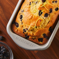 Blueberry lemon bread in a 9"x5" Nonstick Loaf Pan on a wooden surface, showcasing the playful charm of Disney-themed bakeware.