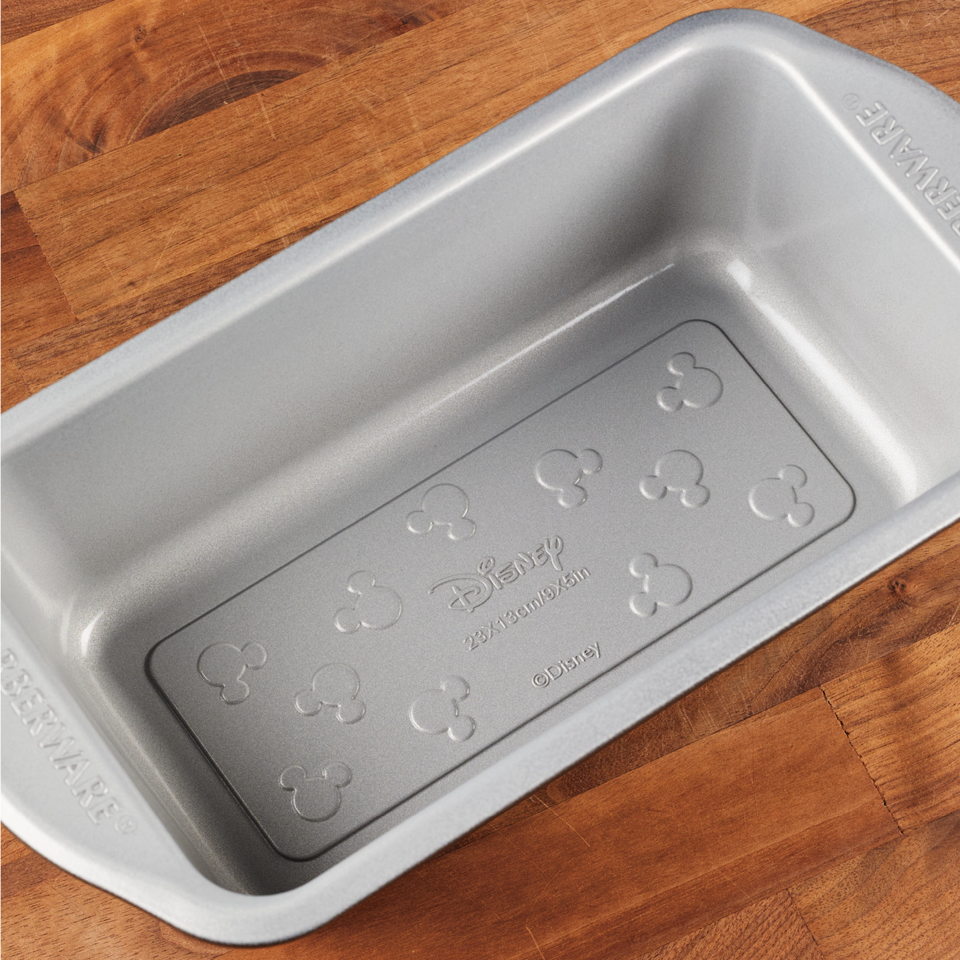 9"x5" Nonstick Loaf Pan displayed on a wooden surface, ideal for bringing a hint of Disney magic to your bakeware collection.