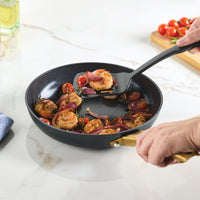 Cooking shrimp and vegetables in the Forged Induction Ceramic 10-Inch Frying Pan on a marble counter.