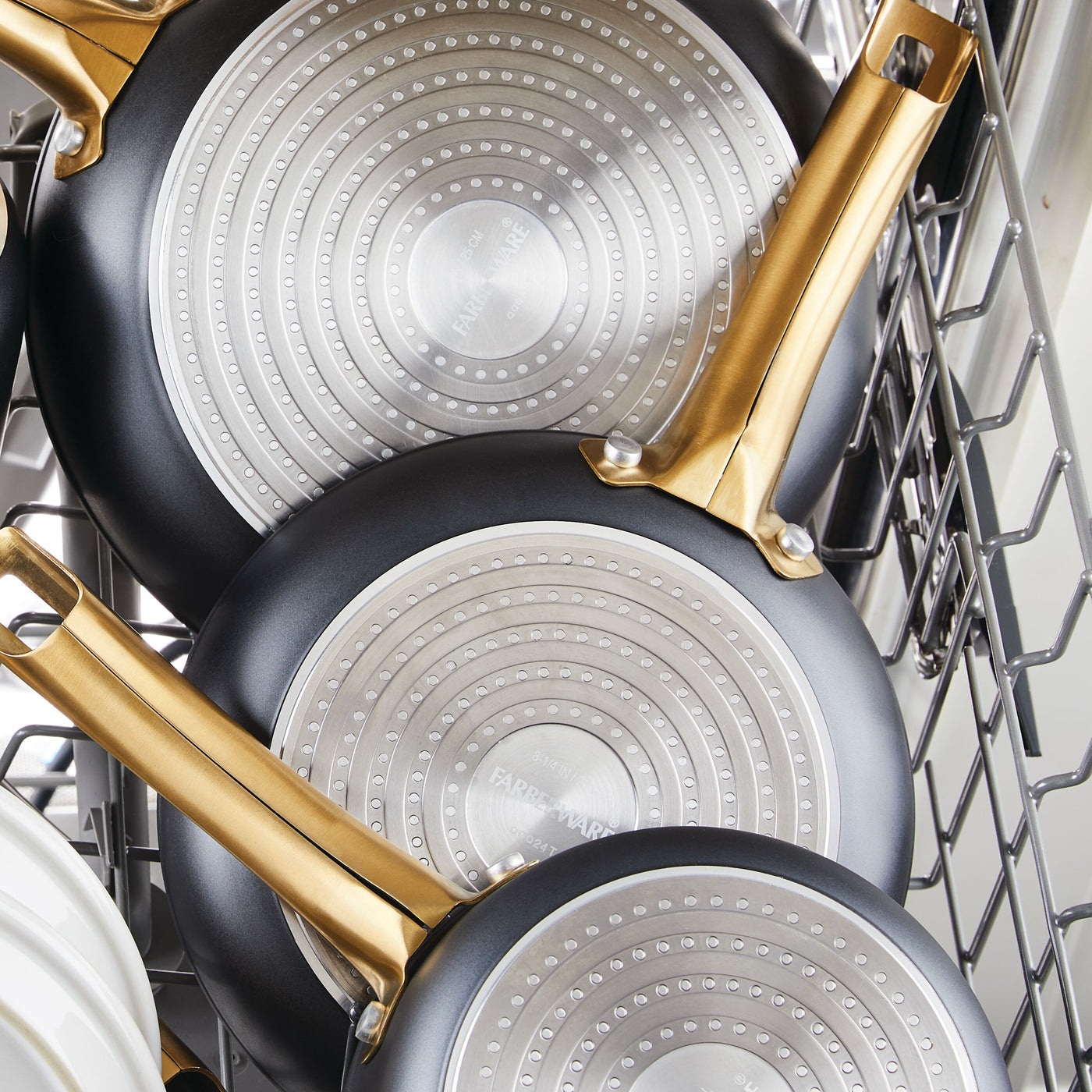 Three 6 Piece Cookware Set pans with gold handles stacked in a dishwasher.
