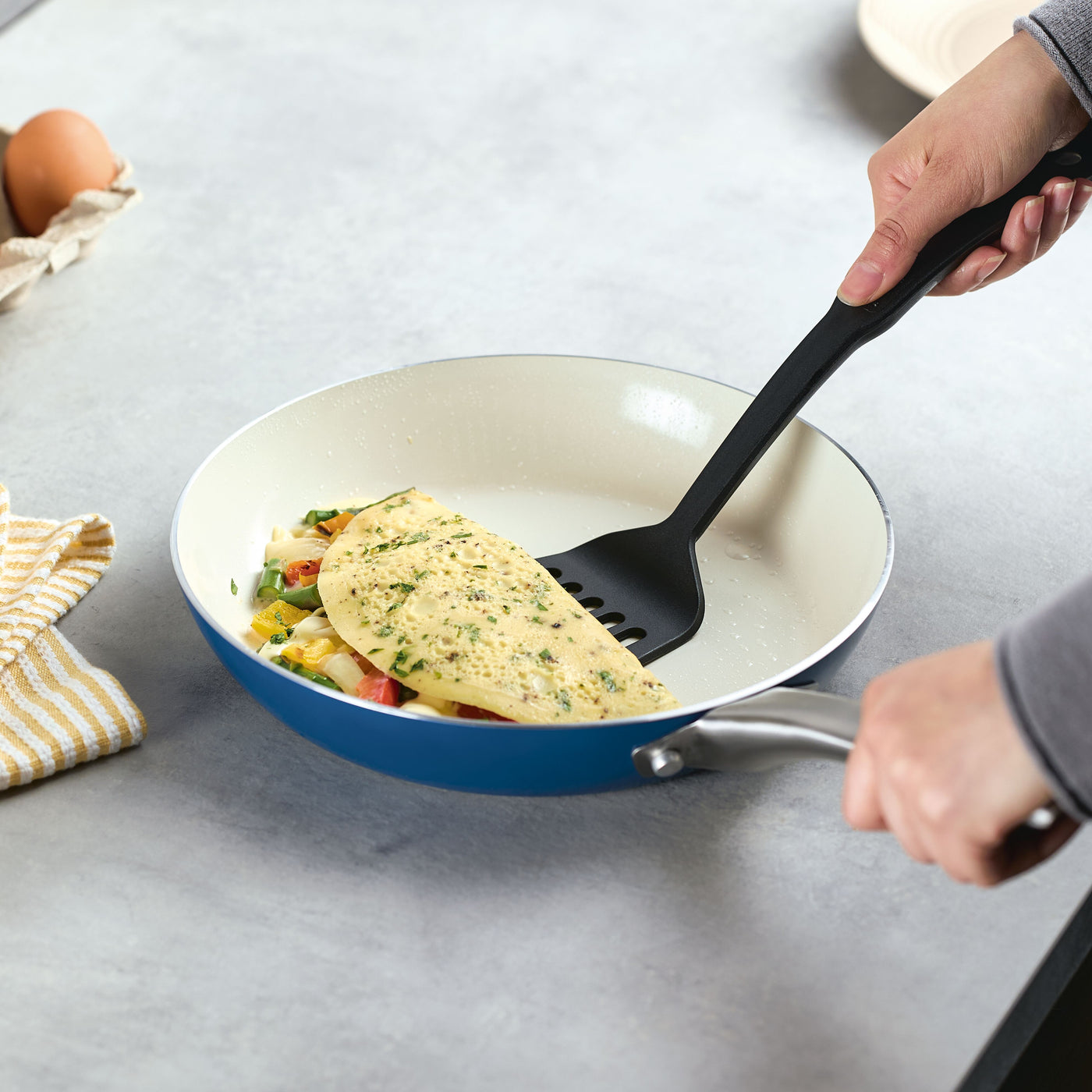 A person is cooking an omelette with vegetables in the 10 Inch Ceramic Nonstick Frying Pan, ensuring a delightful meal while enjoying the pan's elegant design.