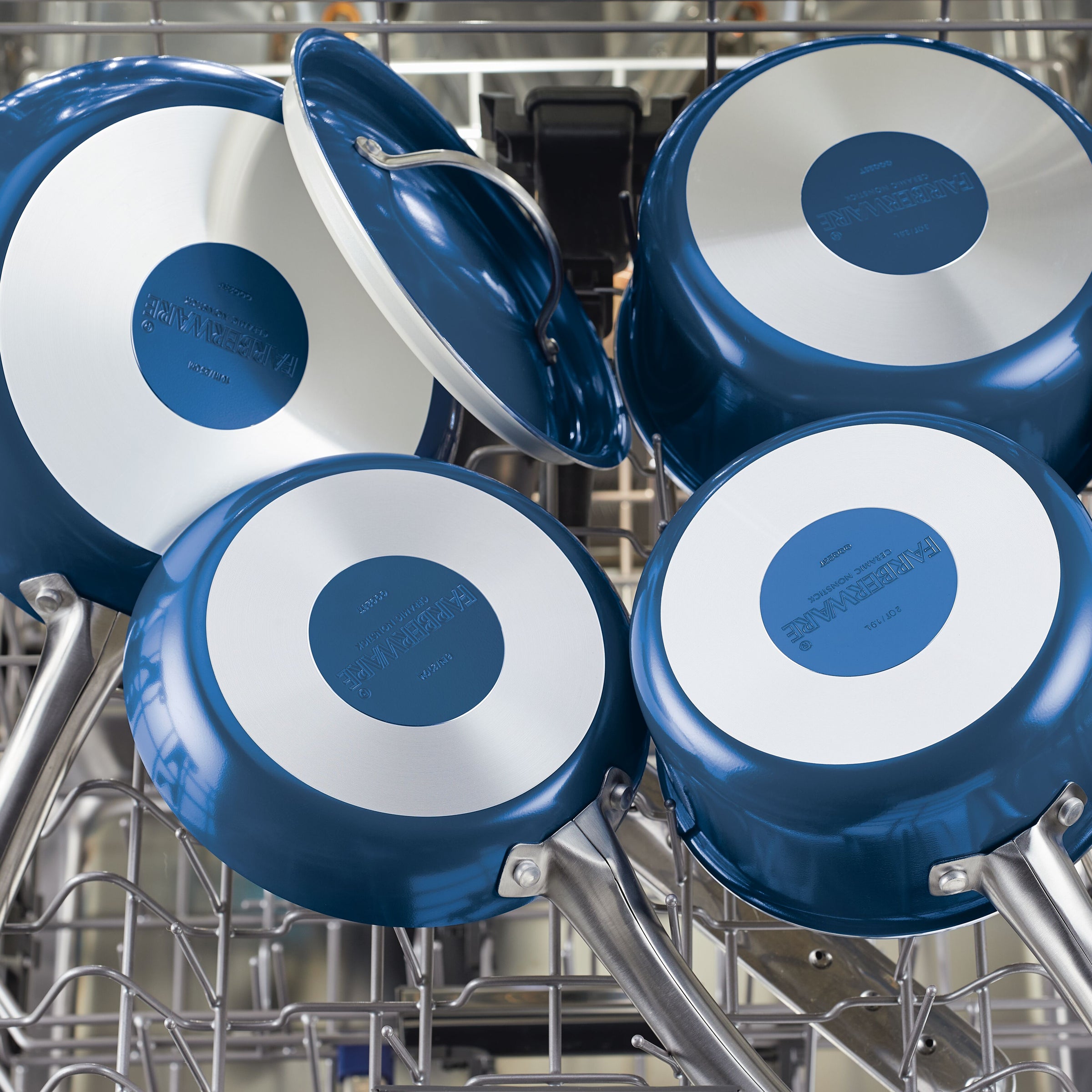 Inside the dishwasher, there are sleek blue 2.75 Quart Ceramic Nonstick Saute Pans with silver bottoms, showcasing a modern elegant design.