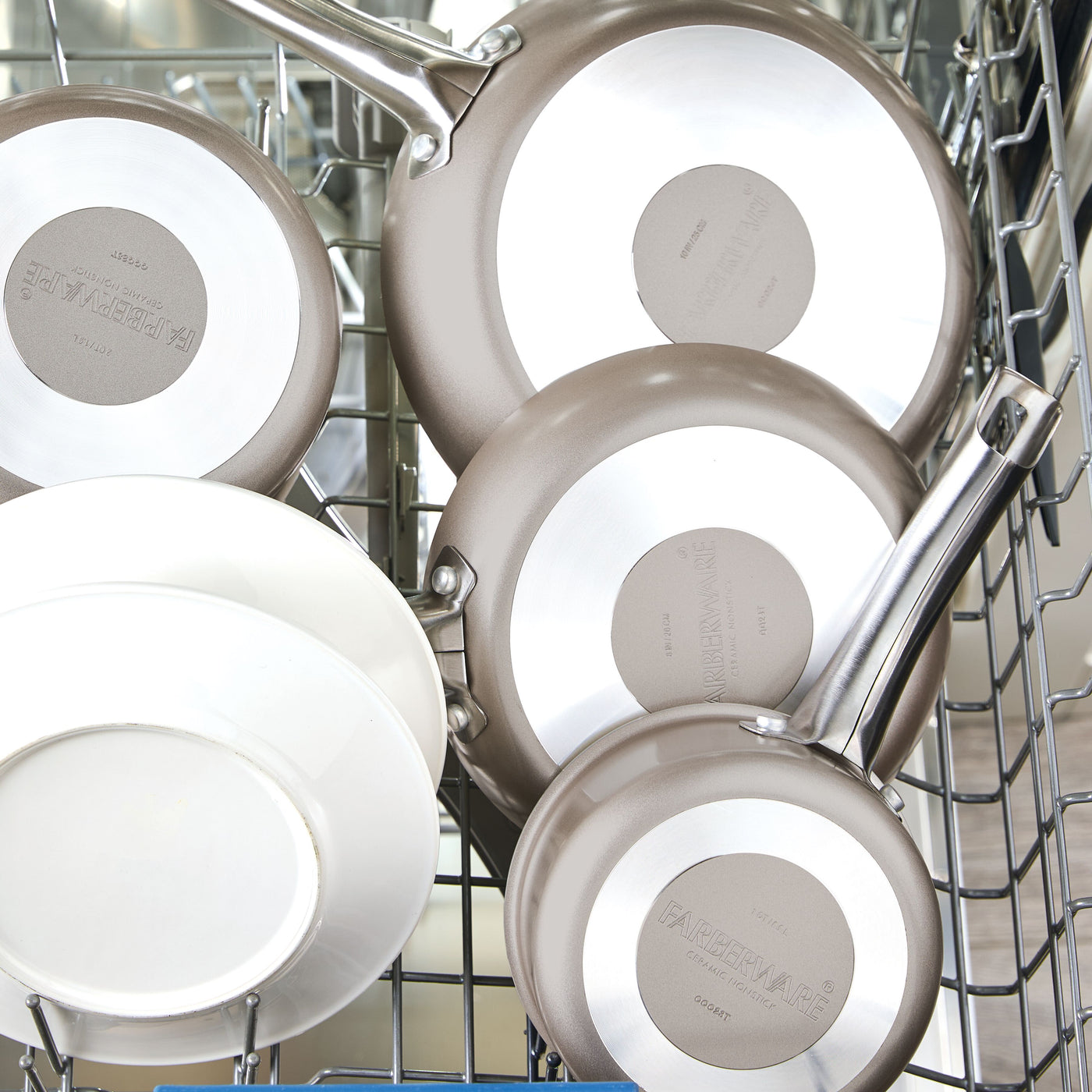 Two Ceramic Nonstick Frying Pan Twin Packs and two white plates in a dishwasher rack.