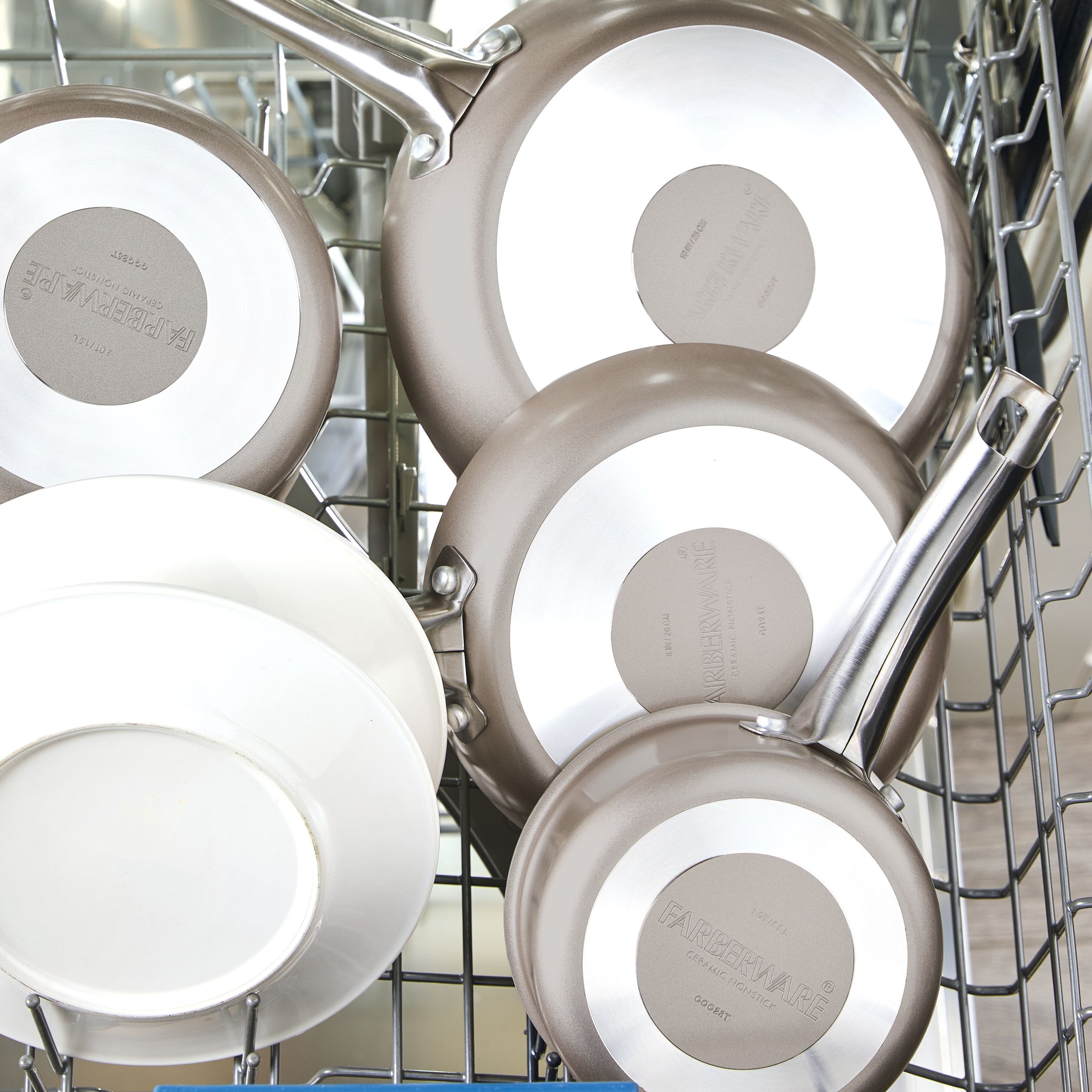 Two Ceramic Nonstick Frying Pan Twin Packs and two white plates in a dishwasher rack.