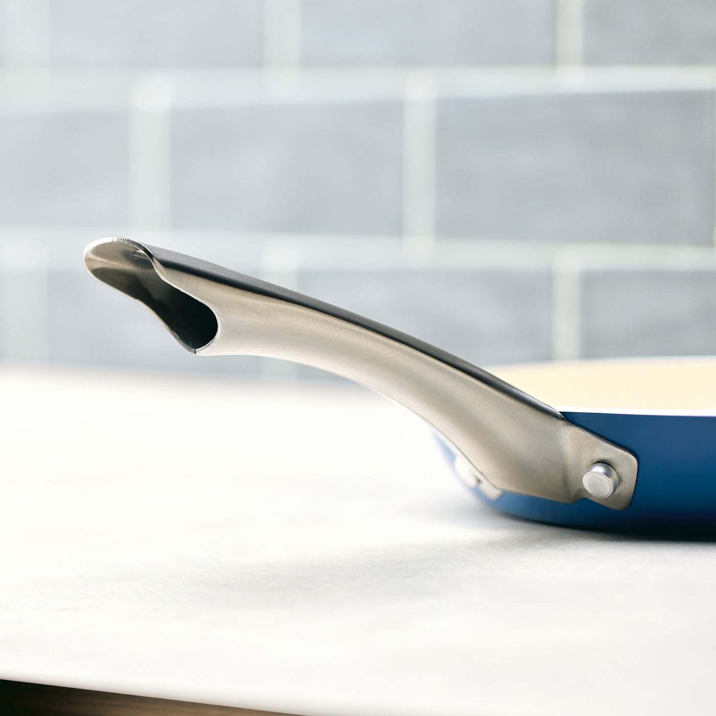 Close-up of the handle of the 10 Inch Ceramic Nonstick Frying Pan on a light countertop, highlighting its elegant design and durable cookware quality.