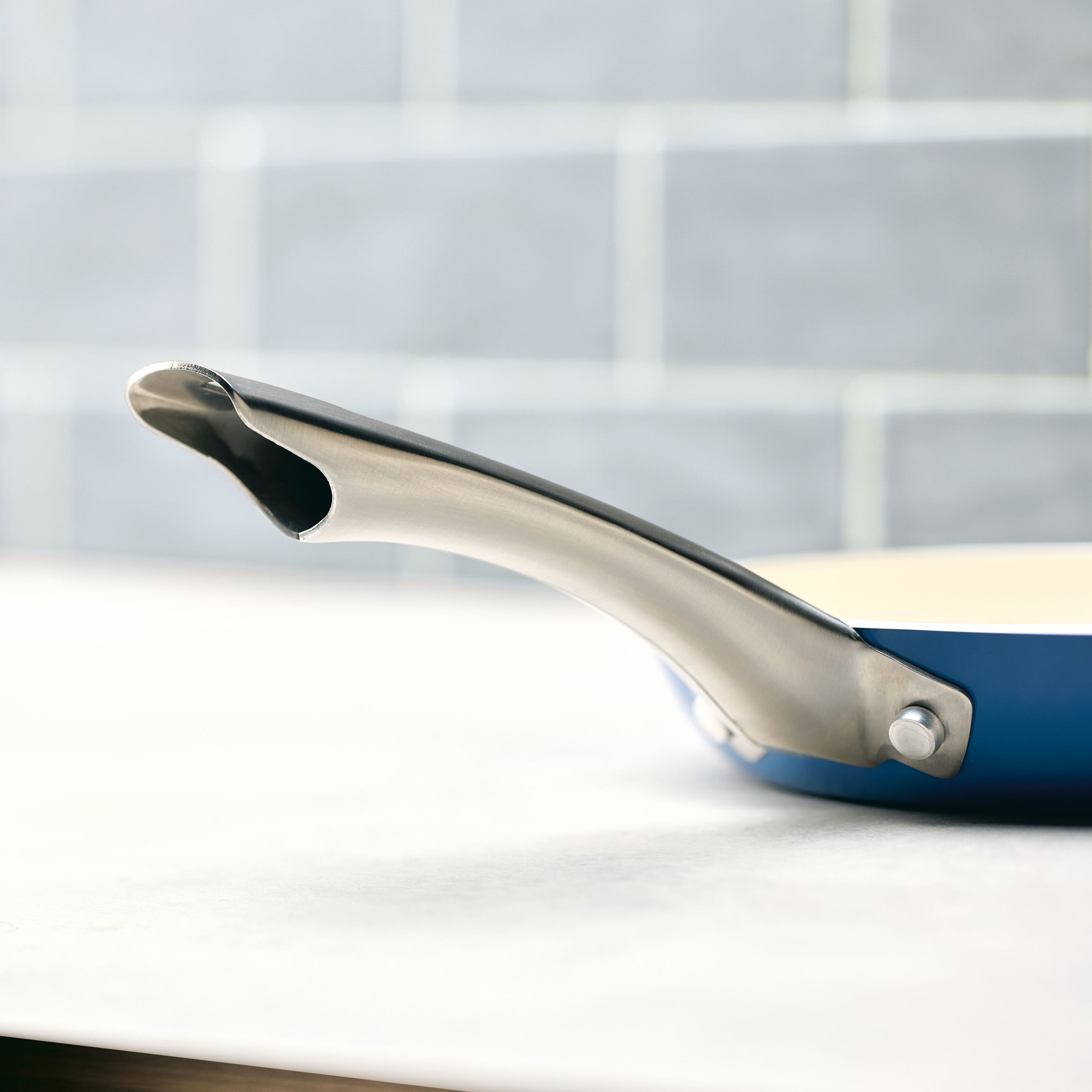 Close-up of the handle of the 10 Inch Ceramic Nonstick Frying Pan on a light countertop, highlighting its elegant design and durable cookware quality.