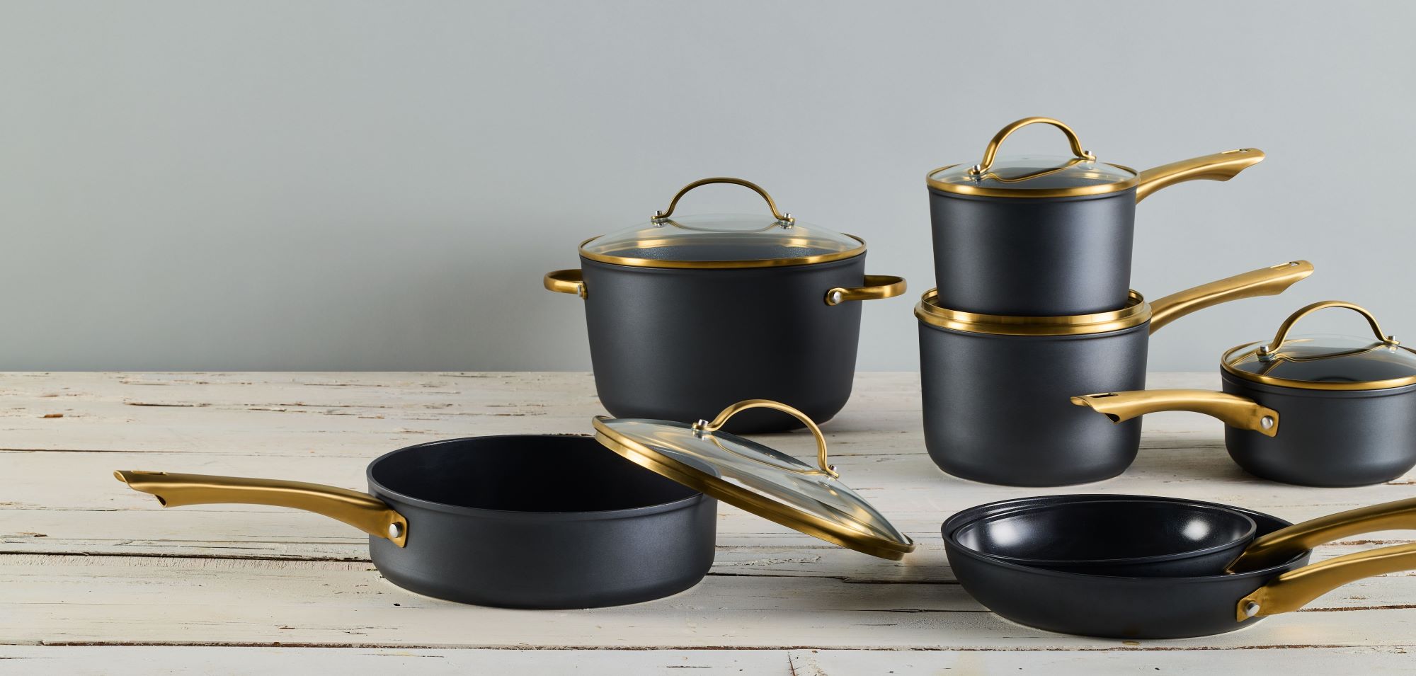 Forged Induction Cookware on white wooden table and a light blue backdrop.