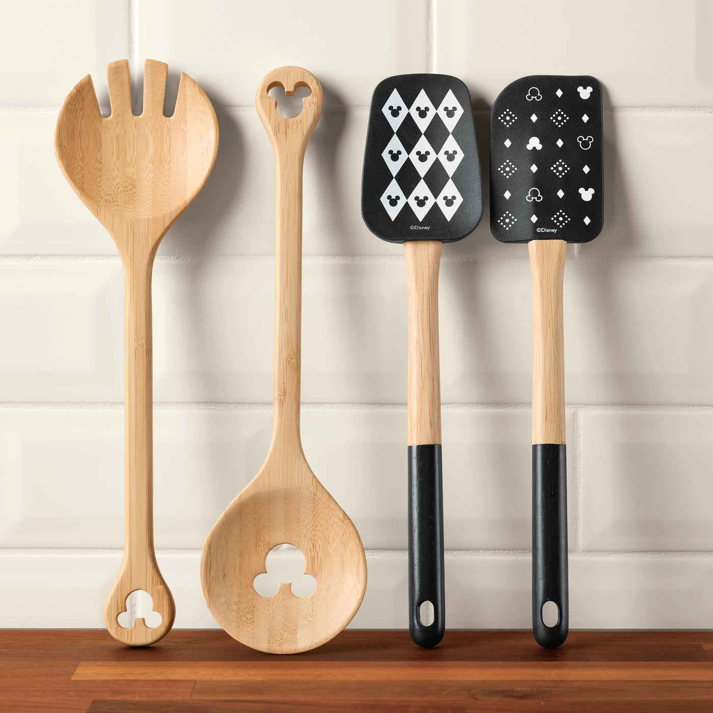 The Monochrome Kitchen Tool Set, with its four utensils showcasing whimsical themed cutouts and patterns, graces the wooden counter, adding a playful charm to your culinary space.