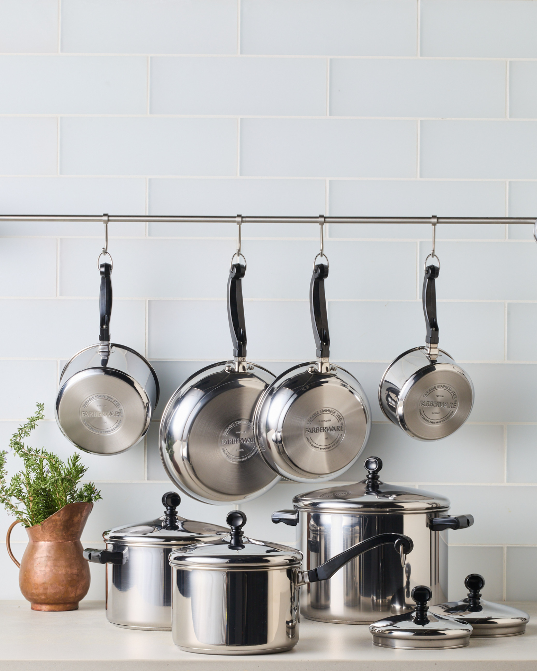 Classic Series stainless steel cookware set on a kitchen counter with some cookware hanging.