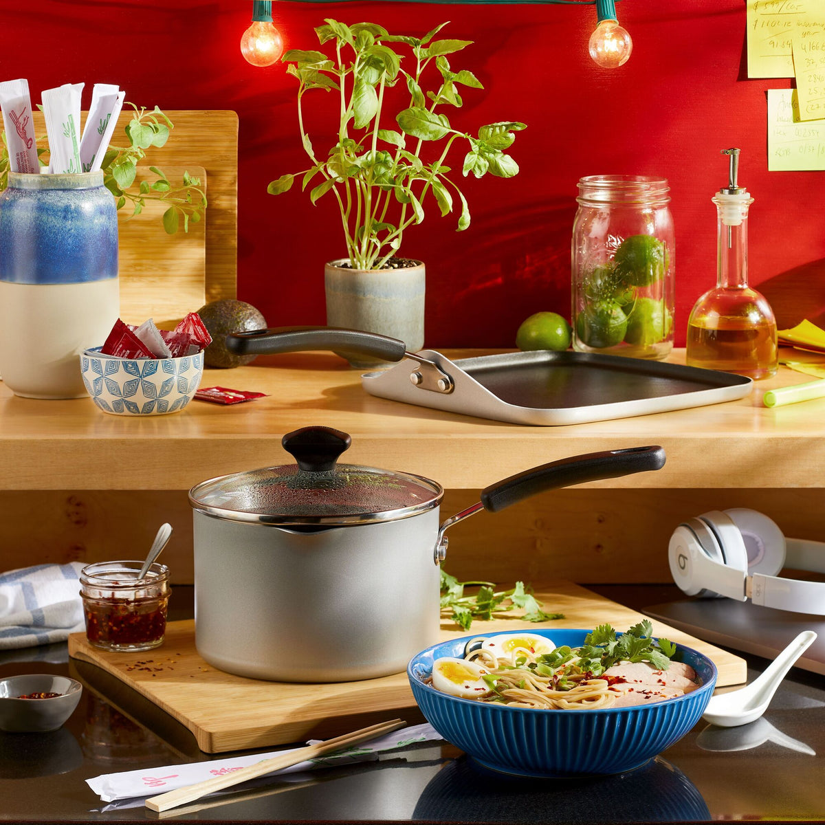Kitchen counter with pots, herbs, and pasta in a blue bowl.