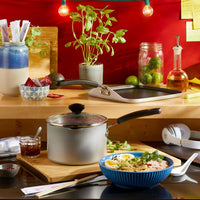Kitchen counter with pots, herbs, and pasta in a blue bowl.