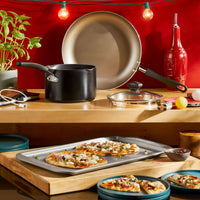 Kitchen counter with cookware, pizza on tray, and string lights.