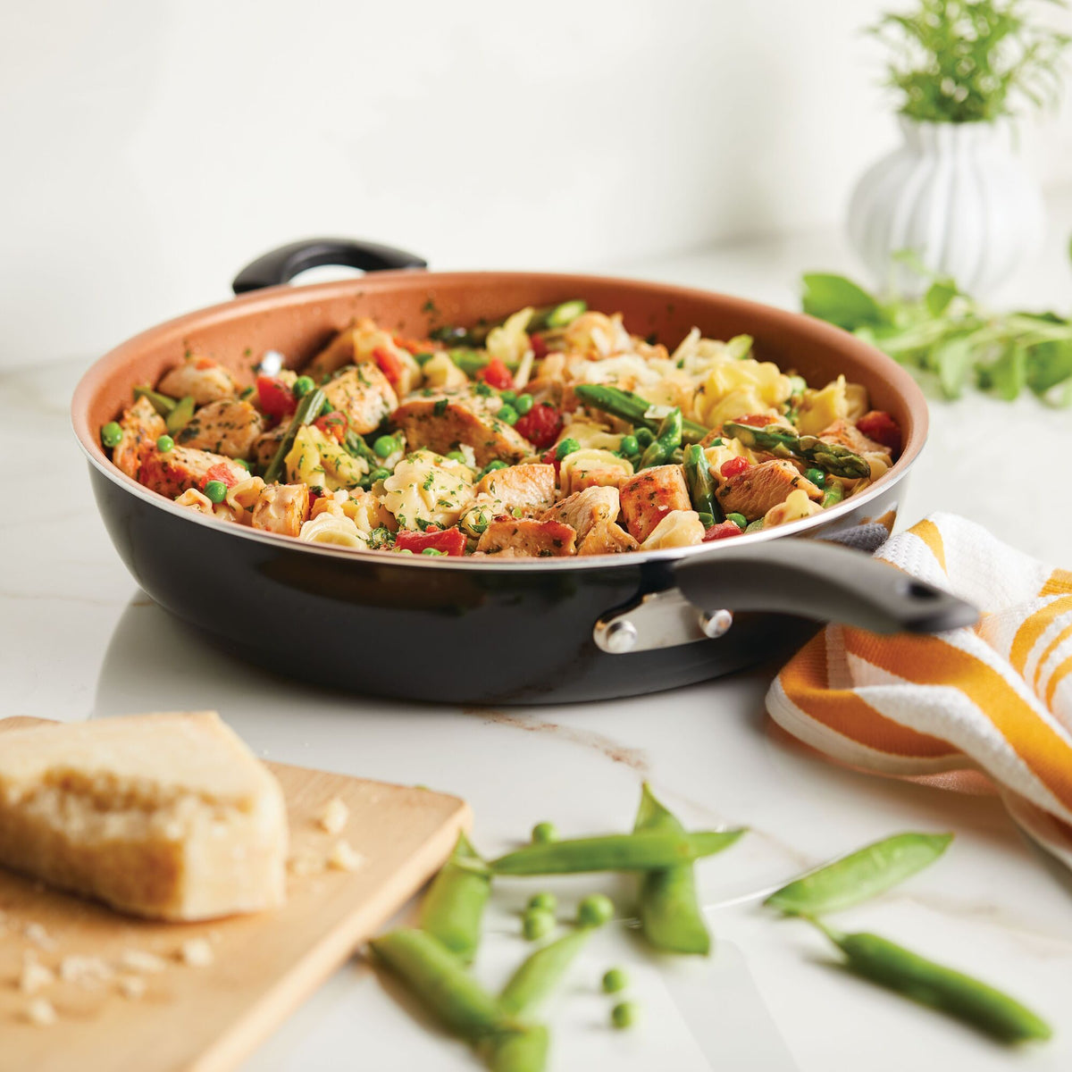 Stir-fried chicken and vegetables in a skillet beside cheese and snap peas.