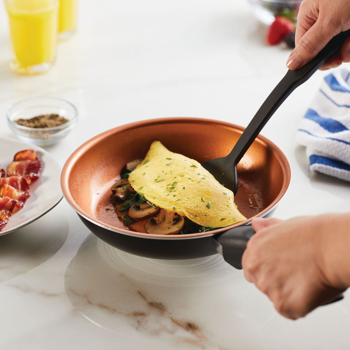 Person cooking an omelette with mushrooms and herbs in a non-stick pan.