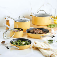 Set of yellow pots and pans with food on a kitchen counter.