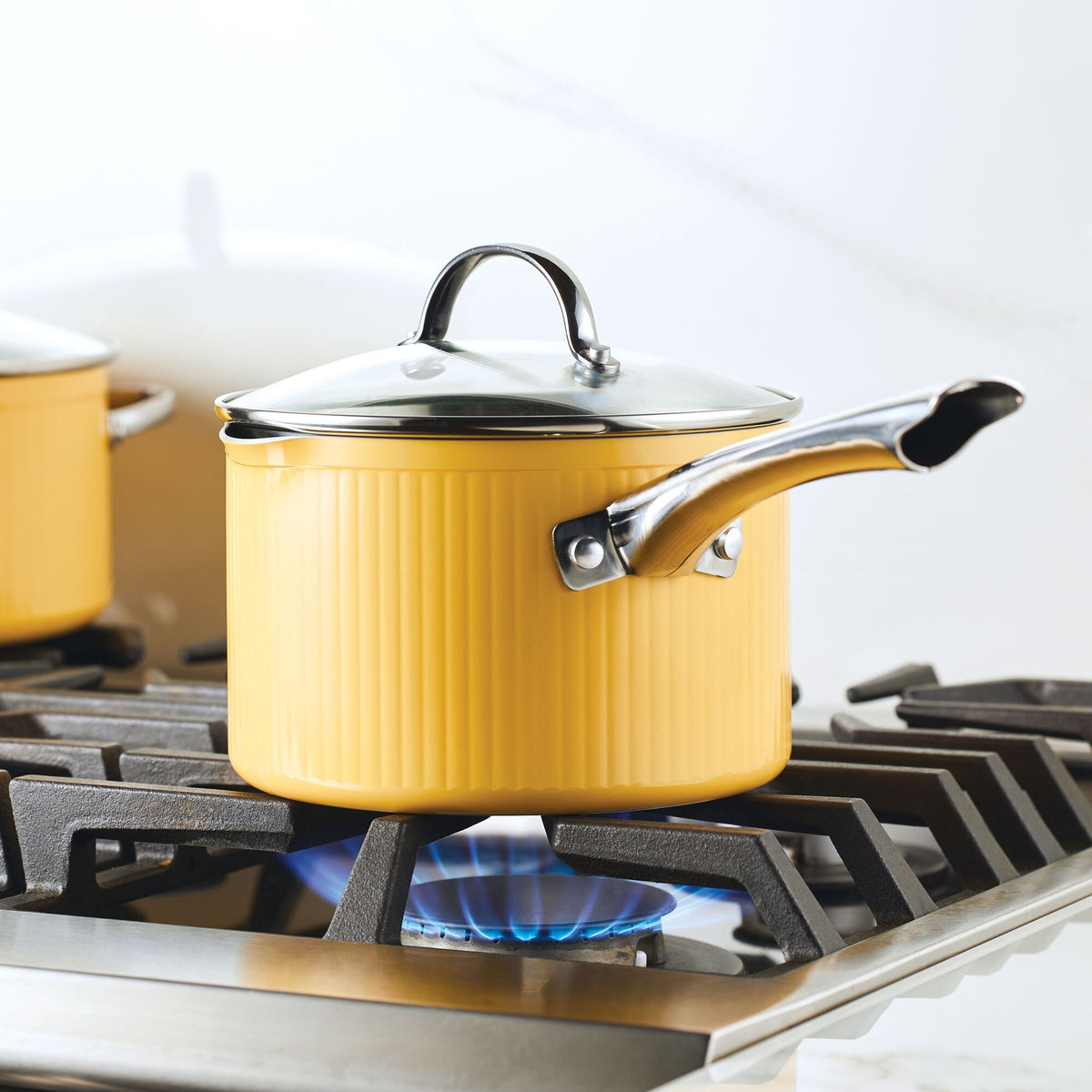 Yellow pot with a lid on a stovetop burner with blue flame.