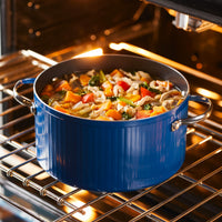 Blue pot with mixed vegetables baking in an oven.