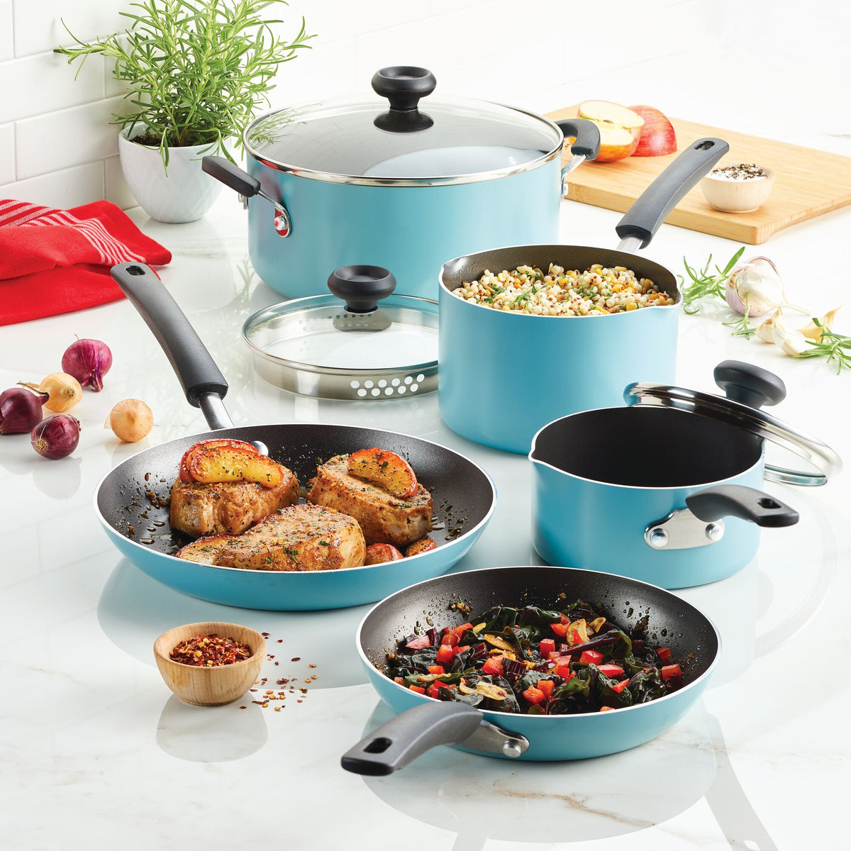 Blue cookware set with food on a kitchen counter.