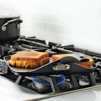 Grilled cheese sandwiches cooking on a stovetop griddle.