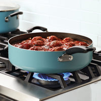 A pot of meatballs in red sauce cooking on a gas stove.