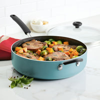 Pan with cooked pork chops, Brussels sprouts, and squash on a kitchen counter.