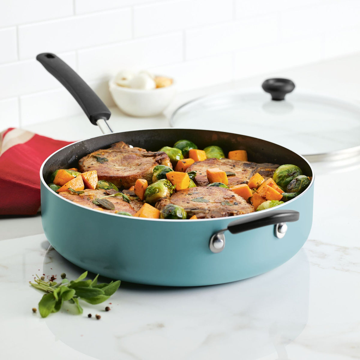 Pan with cooked pork chops, Brussels sprouts, and squash on a kitchen counter.