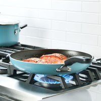 Salmon fillets cooking in a frying pan on a gas stove.