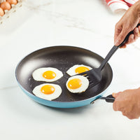 Four sunny-side-up eggs in a frying pan being lifted with a spatula.