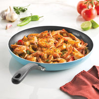Shrimp sautéed with vegetables in a blue frying pan on a white surface.