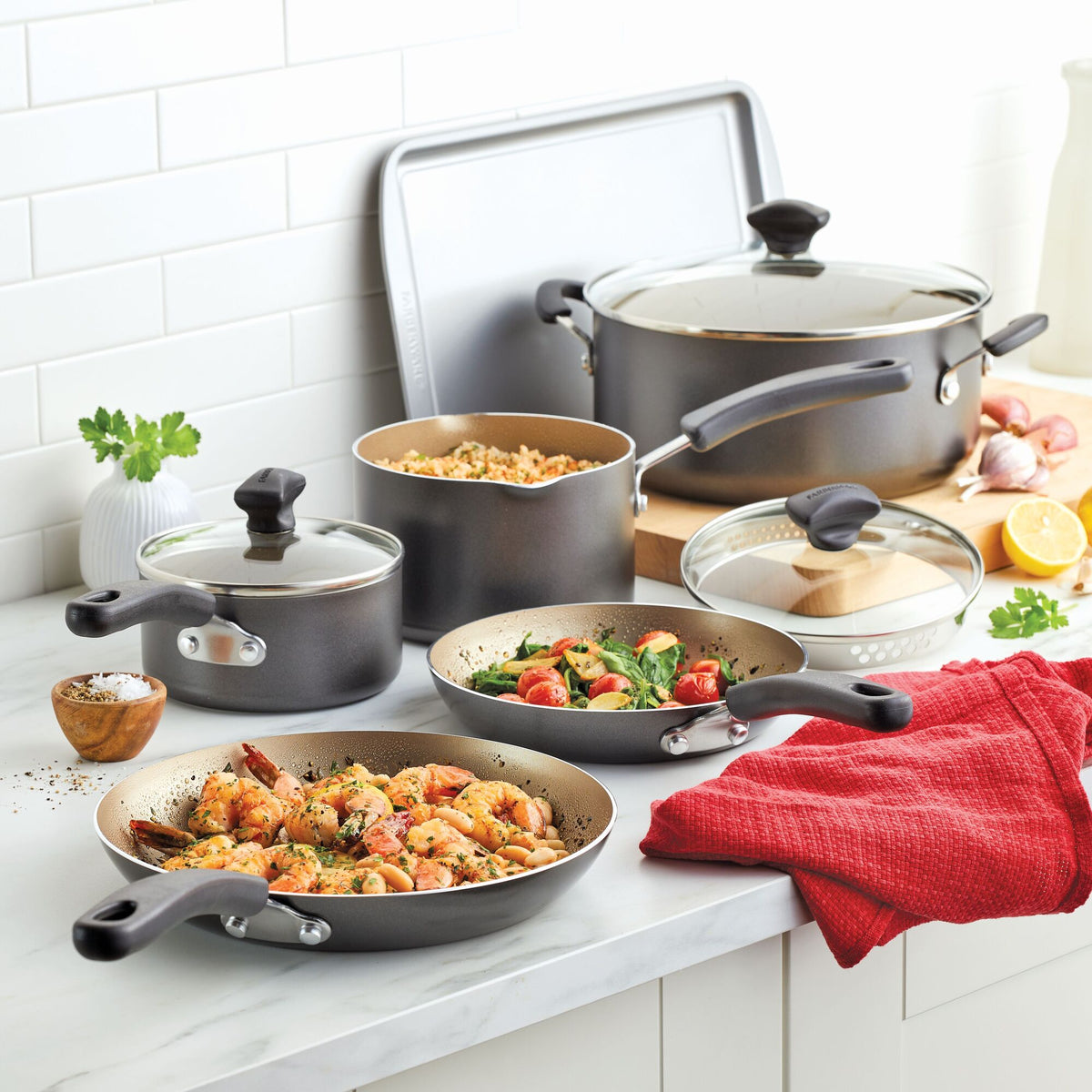 A set of nonstick cookware with food on a kitchen countertop.