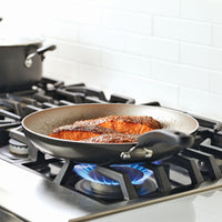 Salmon fillets cooking in a pan on a gas stove.