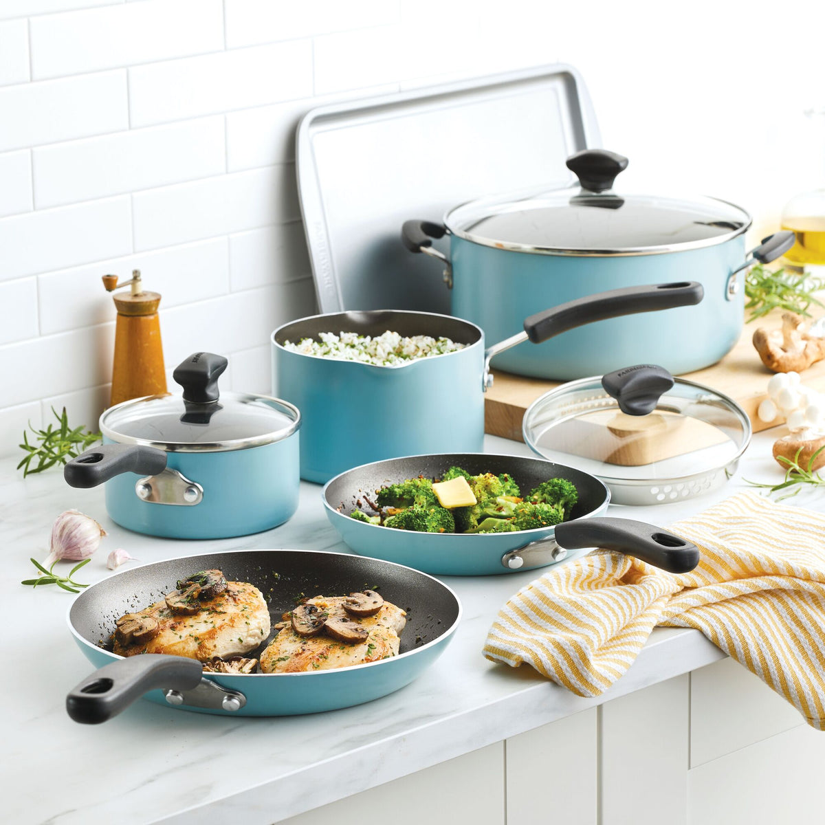 Blue cookware set with food on a white kitchen counter.