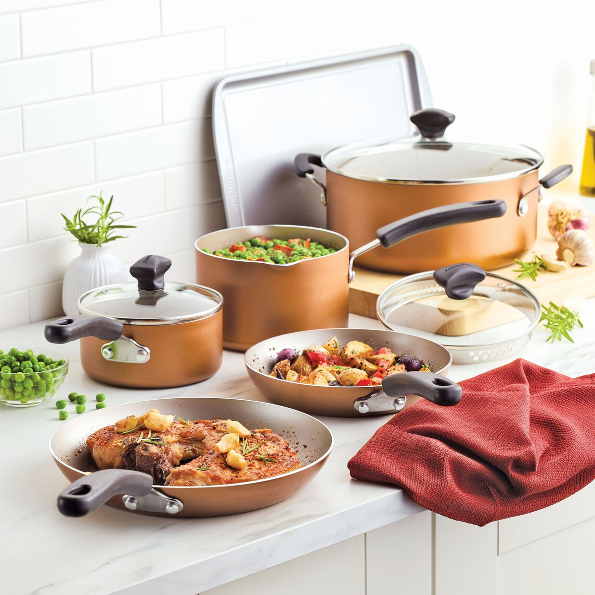 Copper cookware set with assorted dishes on a kitchen counter.