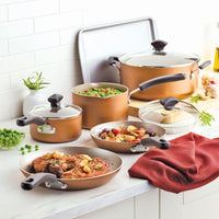 Copper cookware set with assorted dishes on a kitchen counter.