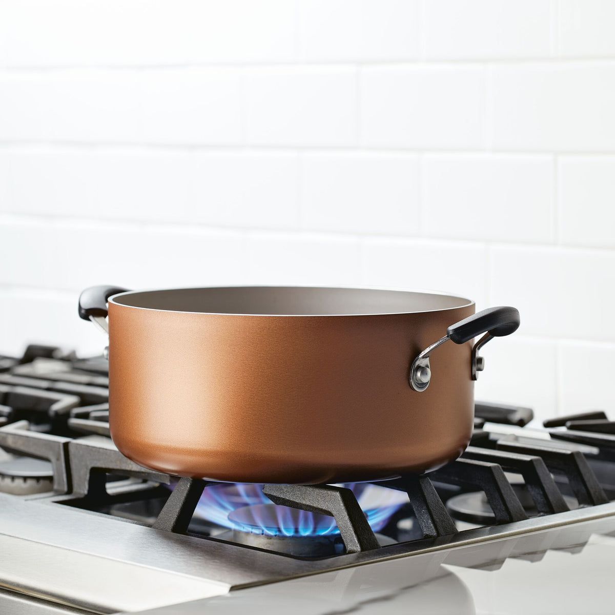 Copper pot on a gas stove with a lit blue flame.