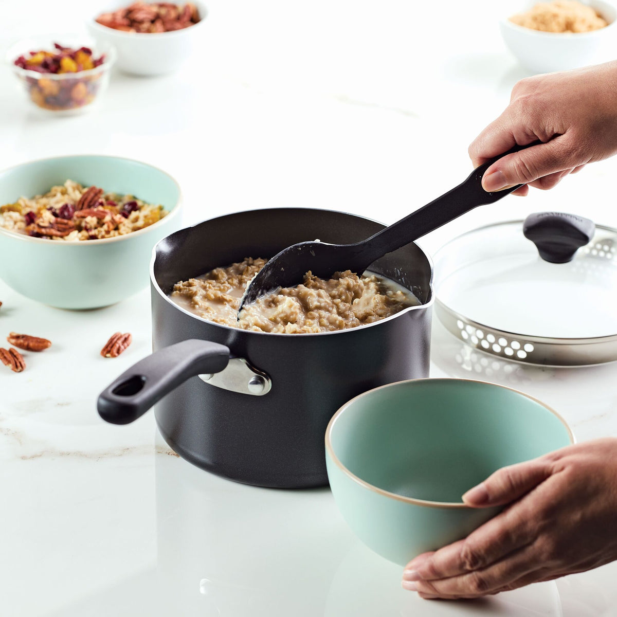 Person serving oatmeal into a bowl from a pot on a countertop.