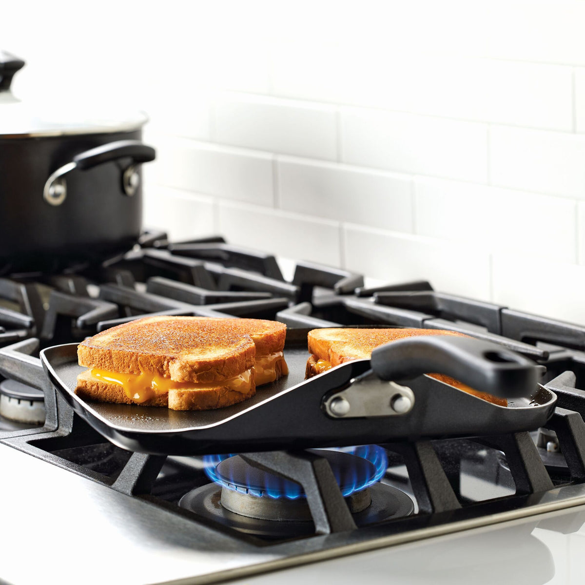 Grilled cheese sandwiches cooking on a stovetop griddle.