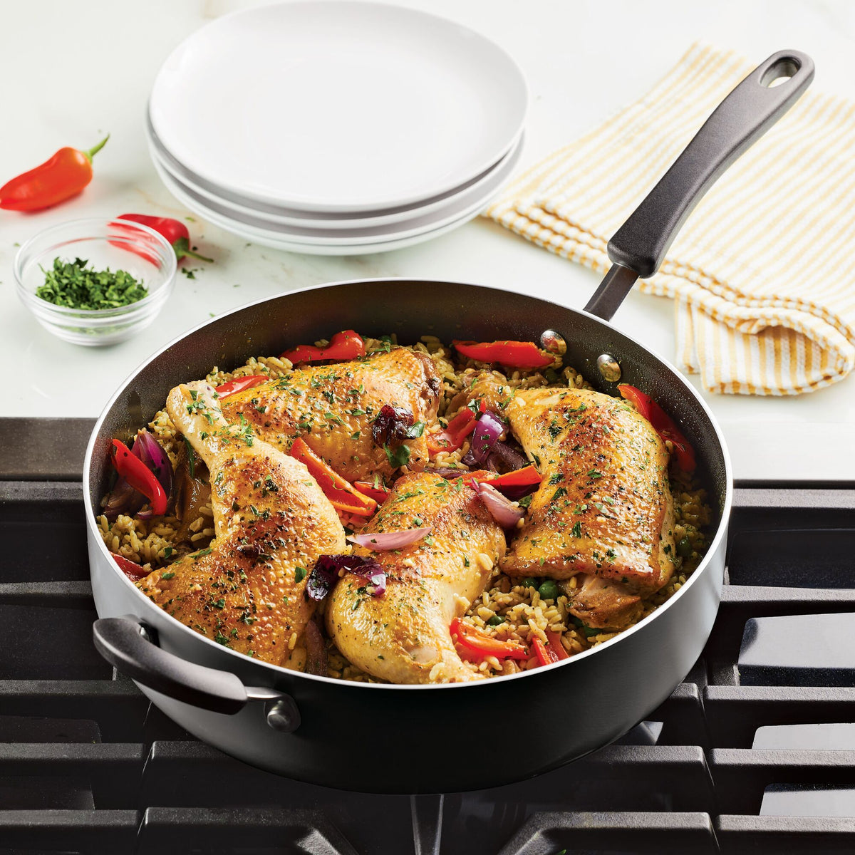 Chicken and rice dish with vegetables in a skillet on a stove.