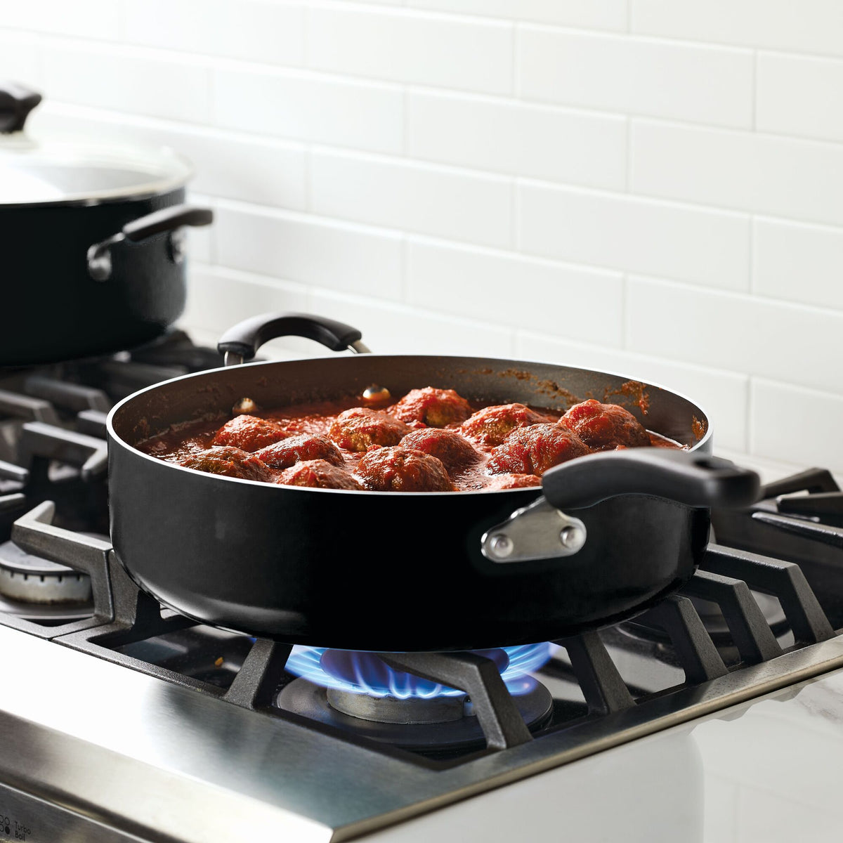Meatballs in tomato sauce simmering in a pan on a stovetop.
