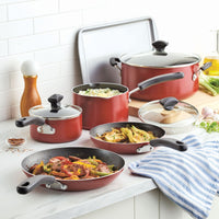 Red cookware set with various pots and pans on a kitchen countertop.