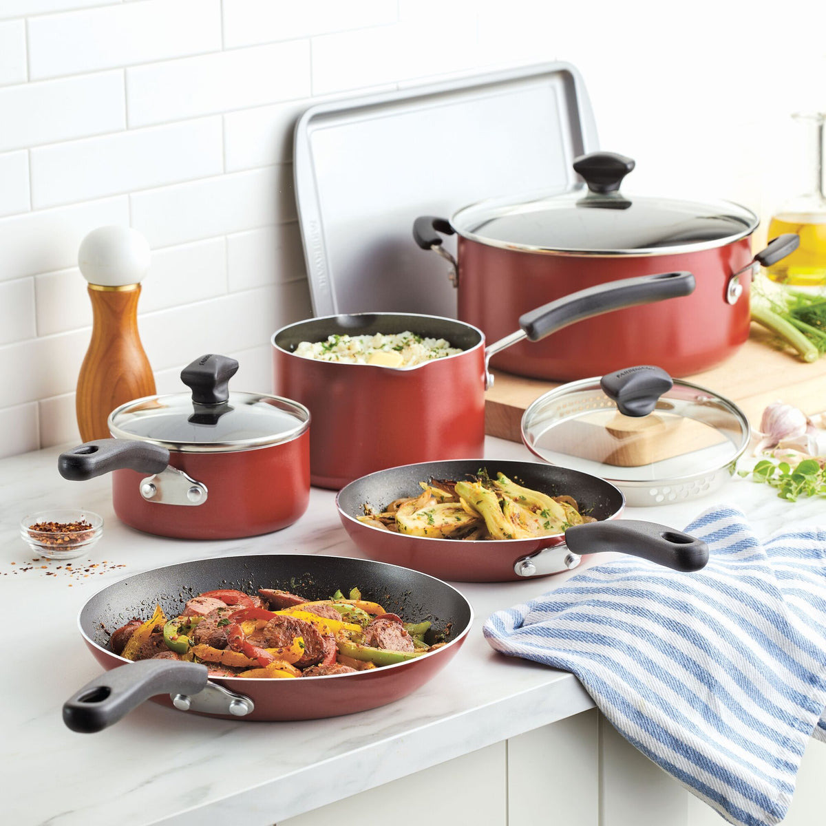 Red cookware set with various pots and pans on a kitchen countertop.