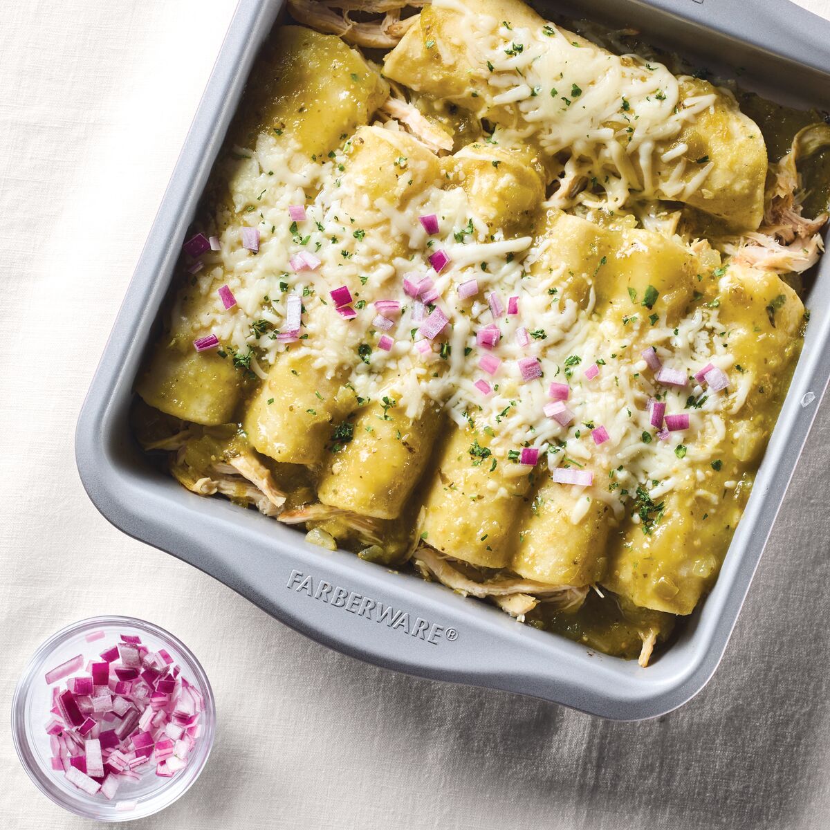 Baked enchiladas with cheese and onions in a baking dish.