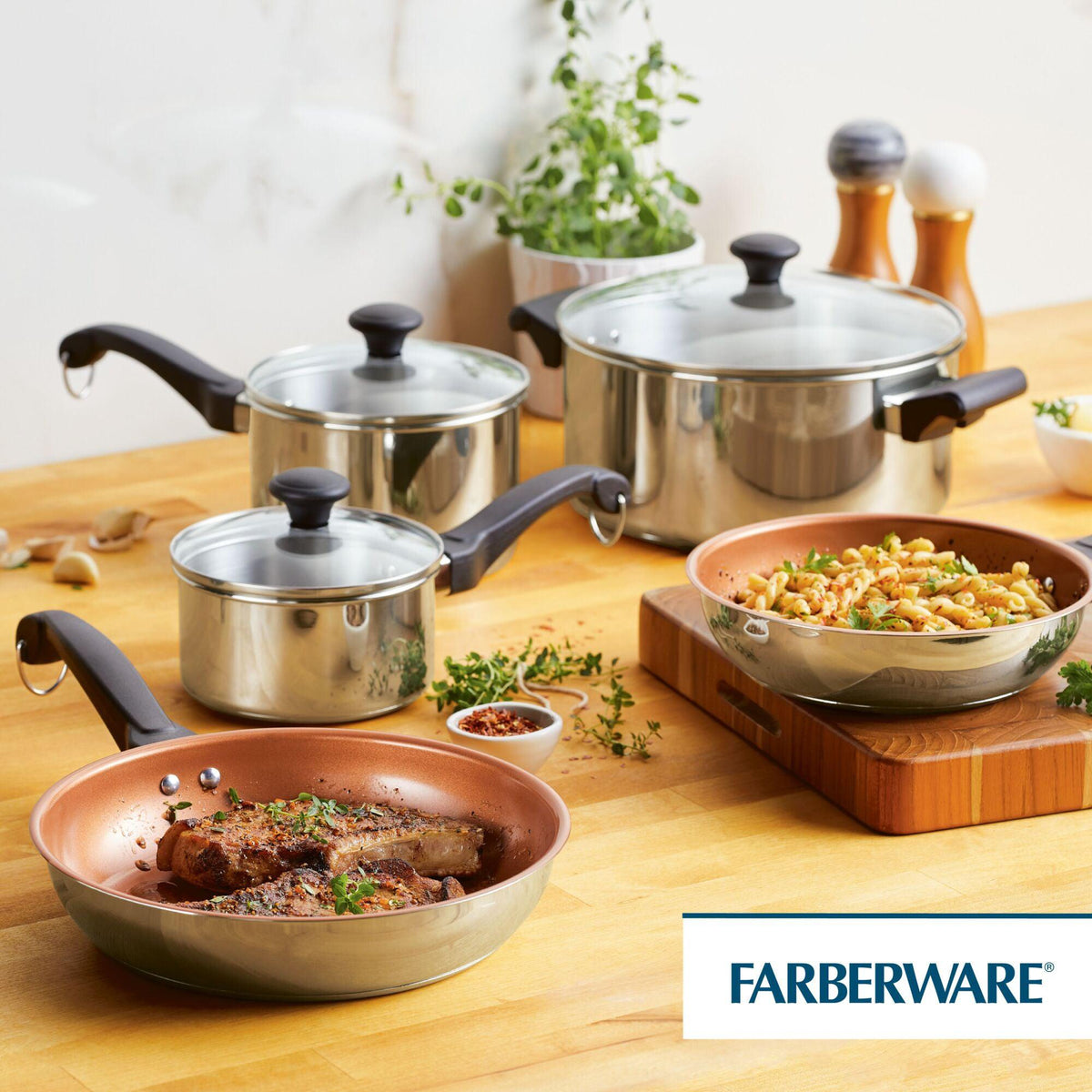 Cookware set with a frying pan and pots on a wooden counter.