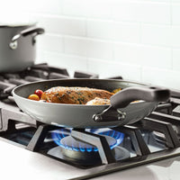 Chicken cooking in a frying pan on a gas stove.
