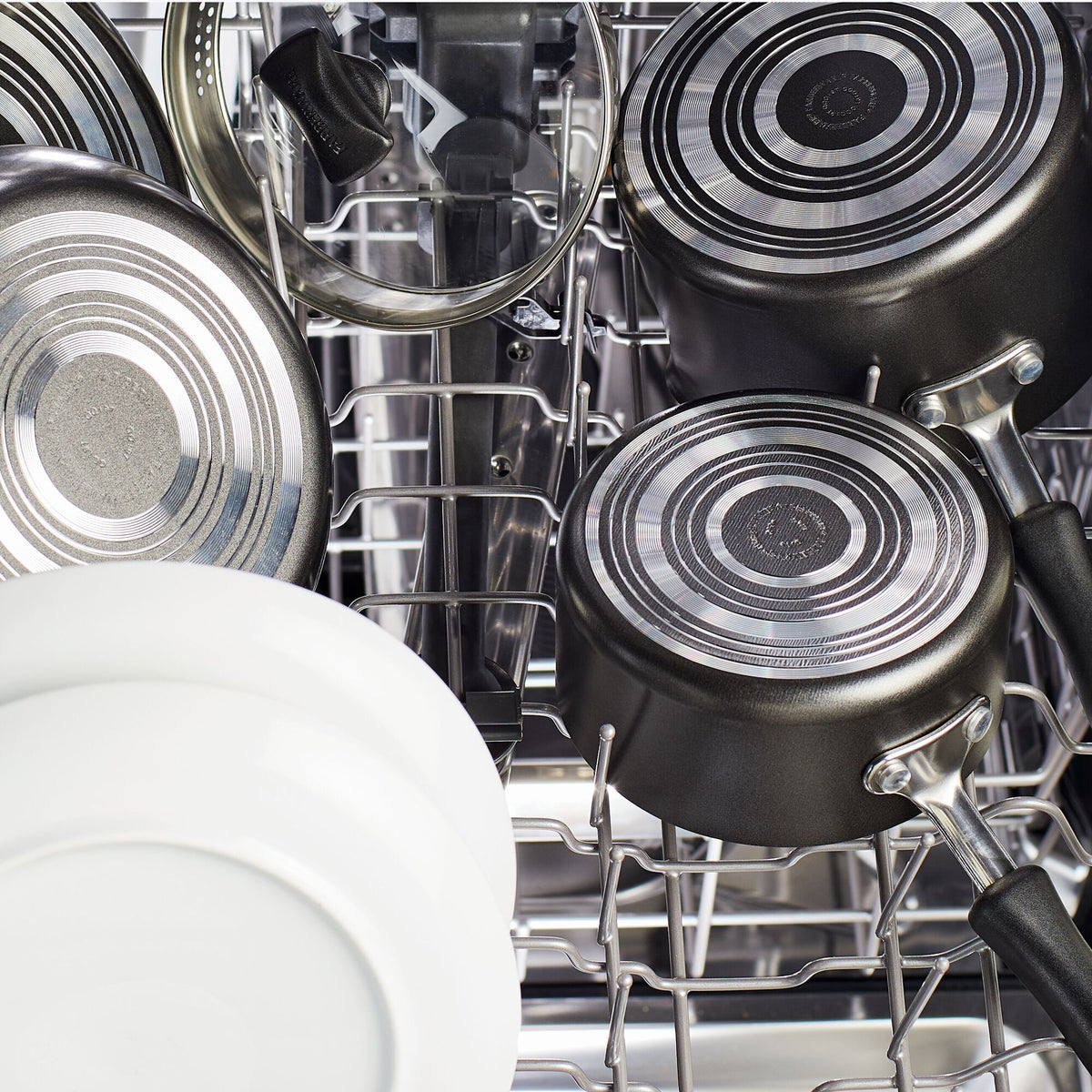 Dishwasher with plates, pots, and a glass lid arranged neatly inside.