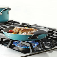 Chicken cooking in a blue frying pan on a stove with a visible flame.